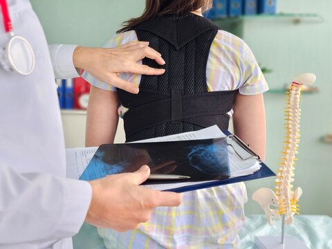 Doctor fits a back brace to a child in a clinic to support the spine and for rehabilitation concept