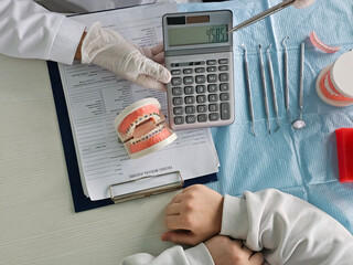 The dentist shows the cost of dental braces on the calculator