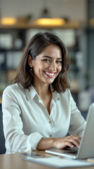 Smiling businesswoman working on laptop in modern office