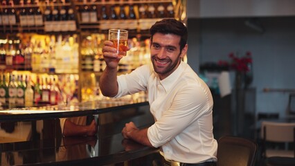 Profile of smiling smart man in white shirt drinking cocktail in Old fashioned looking at camera of special party beverage vibrant on Friday night meeting at luxurious counter bar nightclub. Vinosity.
