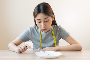 unhappy asian women is on dieting. girl do not want to eat vegetables and dislike taste