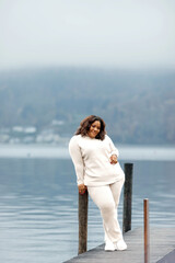 African female adult in white outfit relaxing by tranquil lake