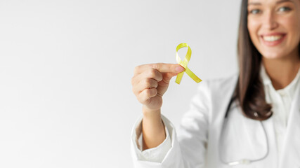 Woman doctor holding yellow ribbon symbol of Sarcoma Bone cancer, Bladder health, Liver disease, Spina Bifida Awareness and Childhood caner