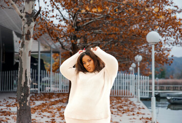 Young african female posing in autumnal urban setting with fallen leaves