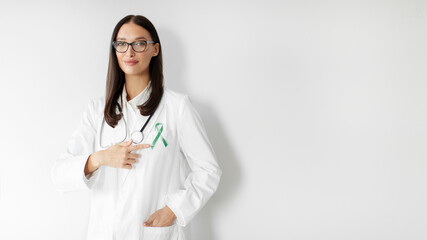 Doctor pointing at green color ribbon symbol for Liver Cancer, Kidney Cancer, Hepatitis B disease, Cerebral Palsy, Glaucoma awareness, Spinal cord injury concept, panorama, free space