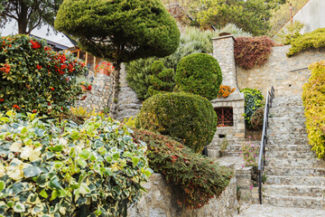 Garden filled with lush greenery, including vibrant shrubs, trimmed hedges, and colorful flowers, nestled within a stone-walled structure.