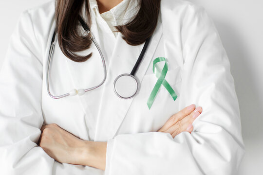 Woman doctor with green ribbon for world Lymphoma, world Mental Health Day, Liver, Gallbladders, bile duct, cervical, kidney Cancer, closeup, cropped