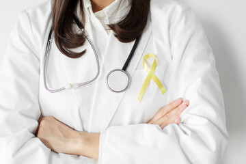 International Childhood Cancer Day. Female doctor in coat with yellow ribbon, closeup. Sarcoma Awareness, bladder cancer concept