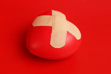 heart figurine with patch on red background. Concept of wounded love
