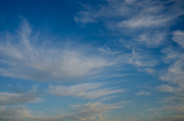 Striking cloud patterns gracefully drift across the deep blue sky at sunset