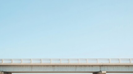 Minimalist view of a concrete bridge against a clear blue sky.