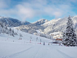 Picturesque snowy mountain landscape with slopes, lifts, and skiers at La Clusaz ski resort,...