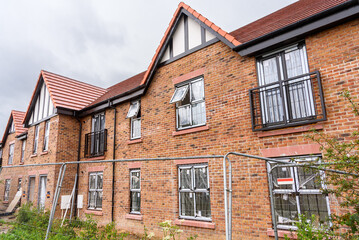 Brick terraced houses under construction in a housing development in the English countryside on a summer rainy day