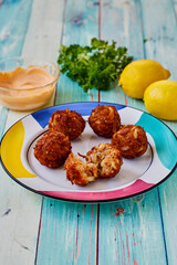 plate of crispy fried crab meatball fritters served with fresh parsley and lemon