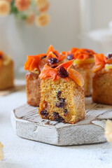 Delightful carrot cake squares topped with creamy frosting and mixed fruits on a rustic wooden platter in a cozy setting