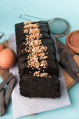Chocolate brownie on a wooden board with egg and cake ingredients on blue background