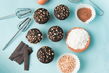 top view and detail Chocolate muffin or cupcake with egg and cake ingredients on blue background. Home baking concept