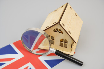 Real estate in United Kingdom concept. Wooden house under magnifying glass on British flag. 