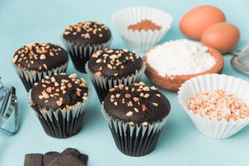 top view and detail Chocolate muffin or cupcake with egg and cake ingredients on blue background. Home baking concept