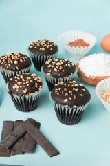 top view and detail Chocolate muffin or cupcake with egg and cake ingredients on blue background. Home baking concept