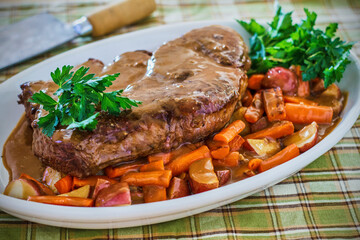 braised beef pot roast on a bed of vegetables topped with gravy