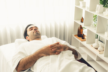Obraz premium Caucasian man customer enjoying relaxing anti-stress spa massage and pampering with beauty skin recreation leisure in day light ambient salon spa at luxury resort or hotel. Quiescent