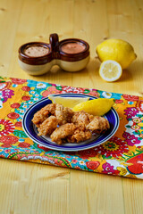 crispy fried oysters with fresh lemon and a remoulade dipping sauce, on wooden tabletop