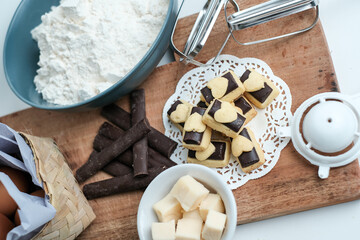 Homemade chocolate cookies on wooden plate with all ingredients, photographed from the top view