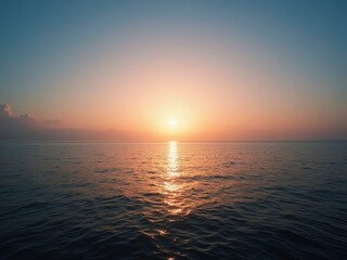 Obraz premium A serene sunset over a mountain range, with the sun dipping below the peaks, casting a warm glow over the landscape.