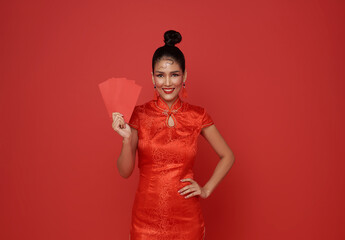 Happy Chinese new year. Asian woman wearing traditional cheongsam qipao dress holding angpao or red...