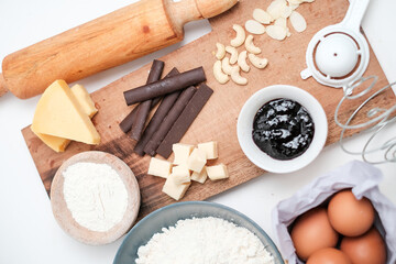 Baking ingredients for chocolate cake muffins or cookies lying ready on wooden kitchen tray. Mise en place, white background, measured ingredients.