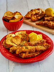 crispy fried fish fillets served with homemade seasoned potato chips on a red plate