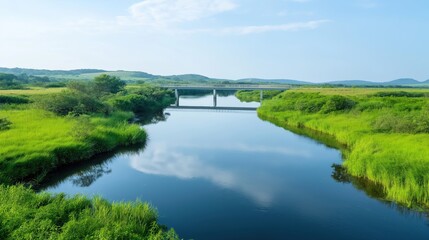 Obraz premium Tranquil river scene with bridge. Calm water reflects serene sky. Green vegetation surrounds riverbanks. Sustainable development in rural setting. Scenic view for relaxation exploration. Eco-friendly