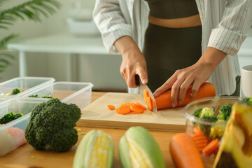 Young woman in sportswear preparing healthy meals on kitchen counter surrounded by fresh ingredients and storage containers.