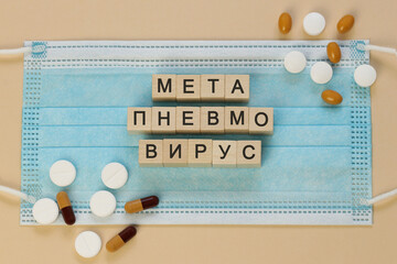 Метапневмовирус - metapneumovirus in Russian, spelled with wooden cubes on a surgical mask, surrounded by pills.   Written in Cyrillic also in languages such as Macedonian, Bashkir, Kyrgyz, Tatar.