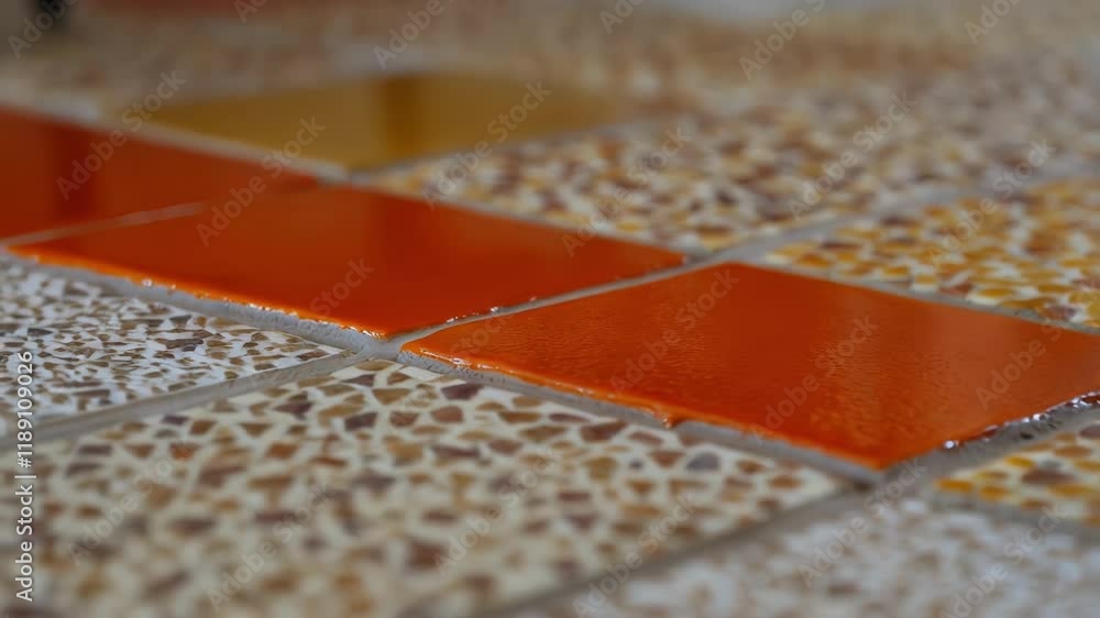 Fototapete Smooth orange tiles contrast with textured beige tiles, creating a distinct pattern on a newly installed floor, showcasing the craftsmanship of tiling work