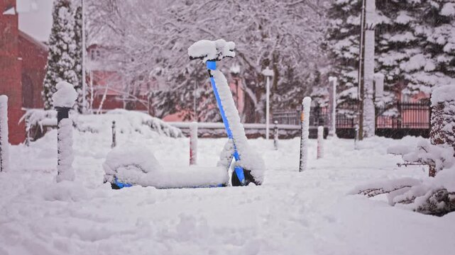 Rentable Shareable Electric Scooter Covered in Thick Snow after Winter Snowstorm Blizzard