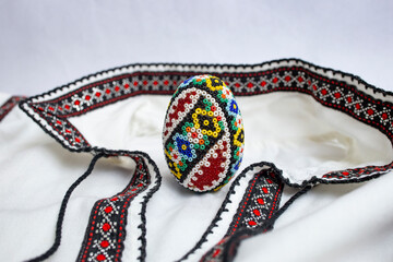 Handmade beaded easter egg. Beadwork, on a romanian ethnic blouse or shirt, soft focus close up...