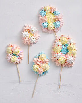 Four dessert pops with colorful frosting arranged creatively on sticks, displaying pastel colors and intricate decorations, perfect for a celebratory event or treat