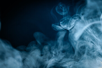 Abstract swirling blue smoke on a dark background, creating a mysterious and ethereal atmosphere. Perfect for artistic, moody, or creative designs.