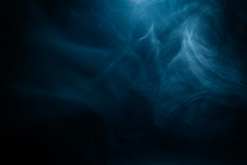 Wispy blue smoke spreads across a dark surface, creating a surreal and atmospheric effect. The intricate swirls add a dreamy and mysterious aesthetic.