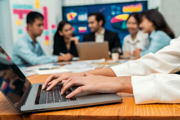 Closeup hand typing keyboard laptop with blurred background of business people using laptop to analyze financial data or data analysis display on screen background. Meticulous