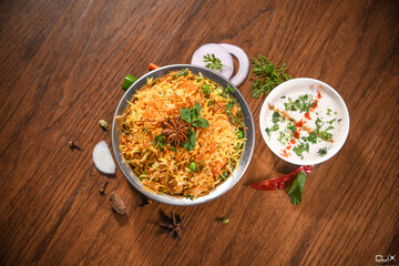 veg biryani in handi with garnish & raita bowl on wooden table background