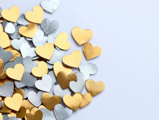 Obraz premium Golden and silver metallic heart shaped confetti scattered on white background