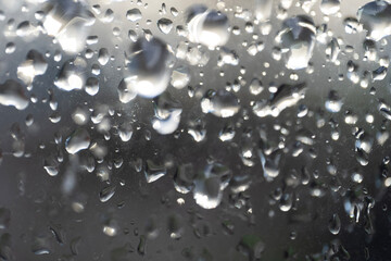 Close up view of water droplets on a glass surface, with soft reflections creating a serene and...