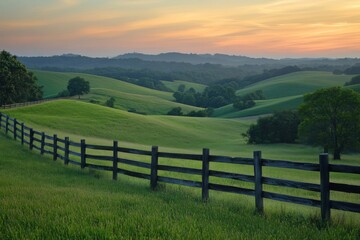 Rolling green hills with a wooden fence under a clear blue sky