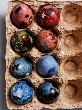 Nine speckled eggs in a cardboard carton showcase an array of vibrant colors and patterns. The distinctive designs highlight the beauty of natural eggs