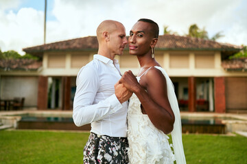 LGBTQ wedding at tropical villa. Ambiguous gender fluid bride in white dress, groom in bold suit dance. Elegant couple in vibrant love story. Inclusive, diverse celebration. Modern wedding.