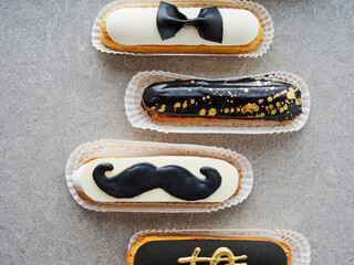 A delightful display of eclairs adorned with decorative toppings like a bow tie and mustache, perfect for an elegant event or celebration, showcasing creativity and craftsmanship
