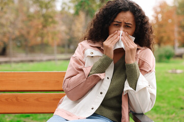 Young woman with runny nose in park